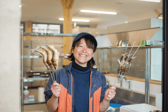 串焼きにした鮎を持つ女性